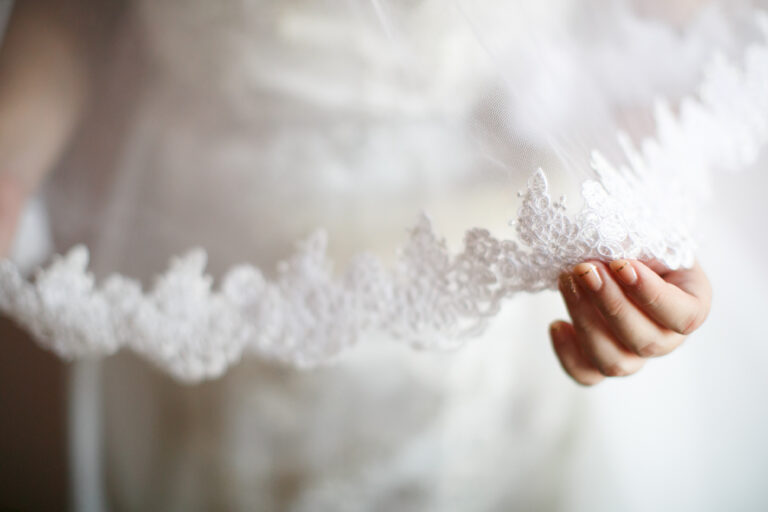 bride in wedding dress holding veil